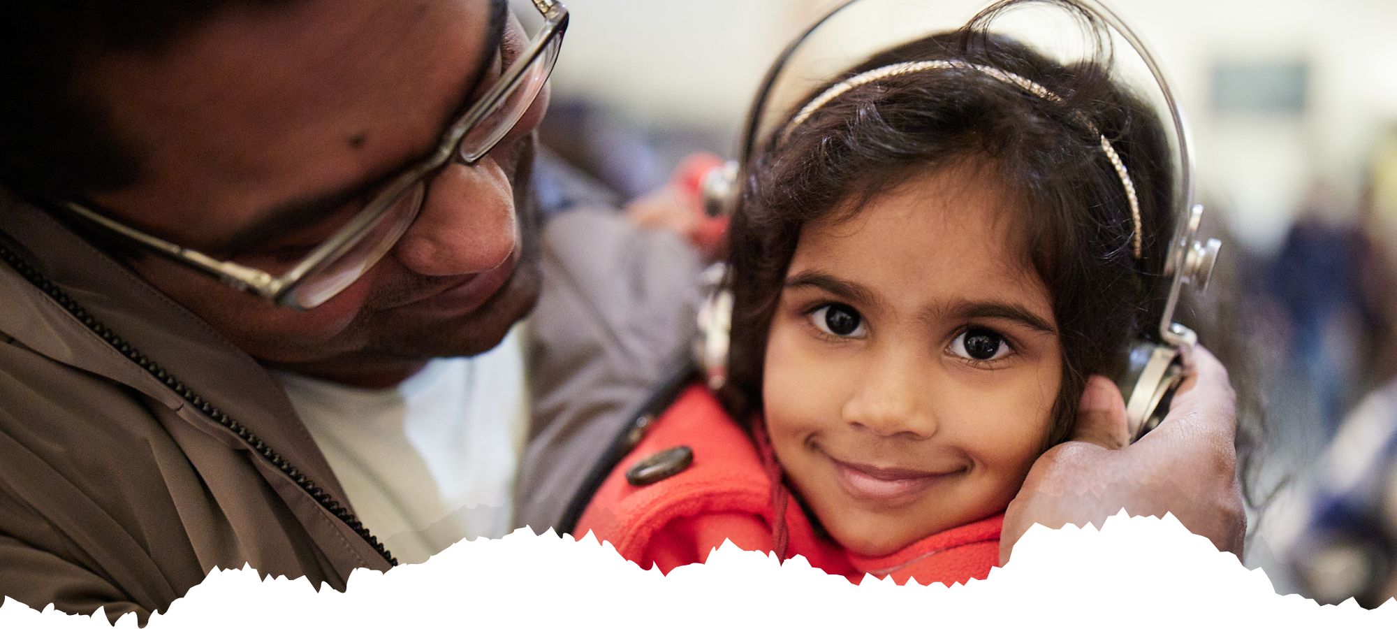 Marconi Day 2022 Young girl with father adjusting headphones for Morse code activity (with 2023 branding)
