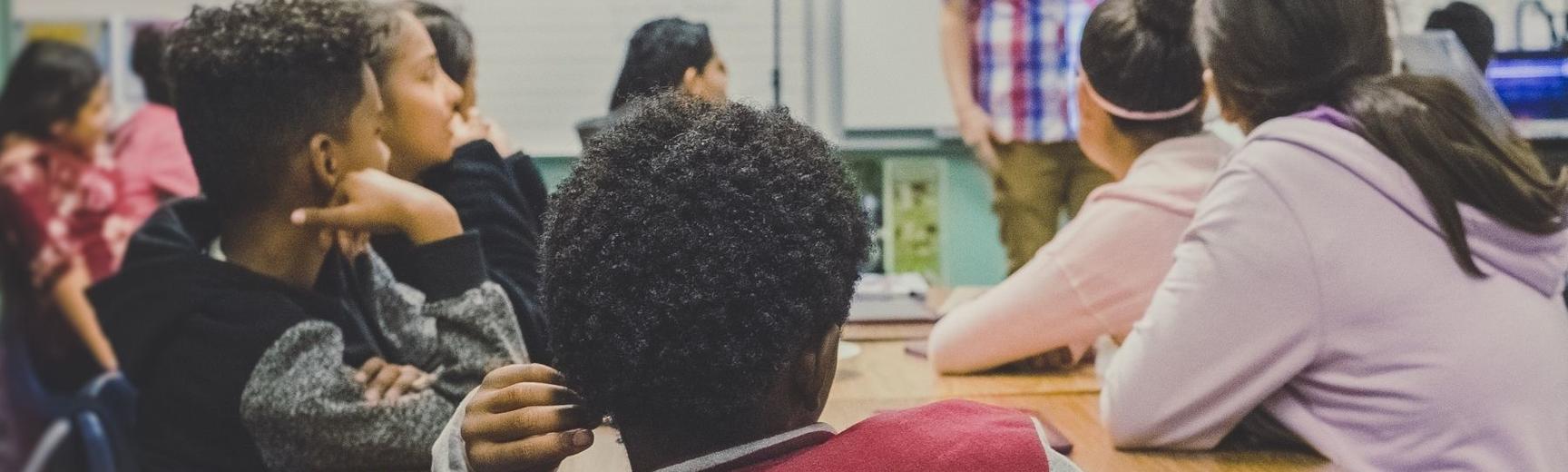 Young people learning with online resources with their teacher in Secondary School classroom (Photo by Neonbrand on Unsplash)