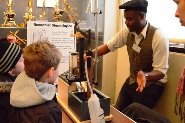 Objects of Invention: student engineer giving a demonstration of a model Newcomen steam pump